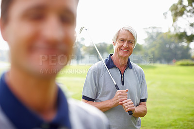 Buy stock photo Portrait of senior man holding a golf club and smiling with son in foreground
