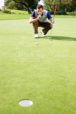 Buy stock photo Full length of man crouching on the putting green and assessing his options to putt the ball