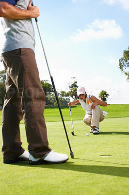 Buy stock photo Young woman eyeing a hole on the golf course with her husband in the foreground