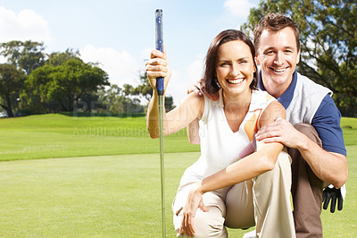 Buy stock photo Young couple smiling and crouched together on the golf course