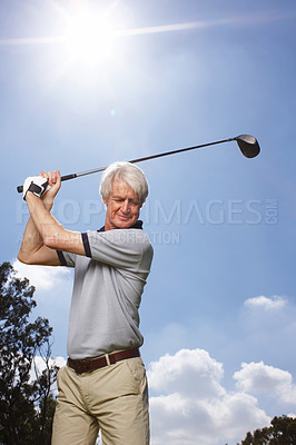Buy stock photo Senior man in full swing during a round of golf against a blue sky