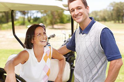 Buy stock photo Smiling woman seated in a golf cart with her husband standing alongside her