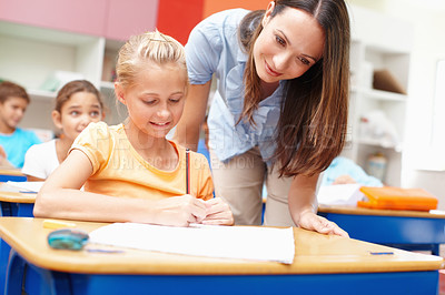 Buy stock photo Classroom, child and teacher with help at desk for learning, knowledge or teaching at school. Academy, woman and girl student with information on paper for education, development or notes for project