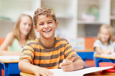 Buy stock photo Sweet schoolboy sitting at his desk in class laughing happily