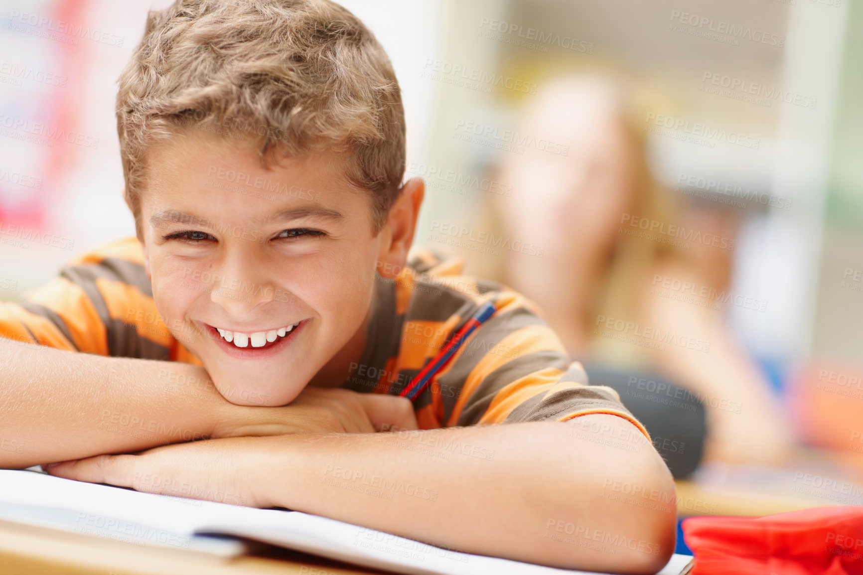 Buy stock photo Happy schoolboy resting his head on his arms and smiling at you - copyspace