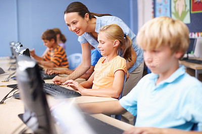 Buy stock photo A happy young teacher assisting students in their computer class