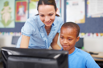Buy stock photo An attractive young woman helping out a young ethnic boy in computer class