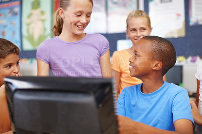 Buy stock photo A group of cute school kids sitting and standing around a computer during class