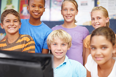 Buy stock photo Portrait of a group of school kids sitting and standing around a computer during class