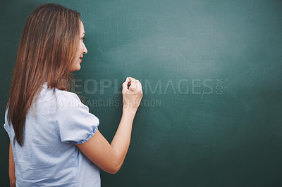 Buy stock photo A pretty young teacher writing  today's lesson plan on the blackboard