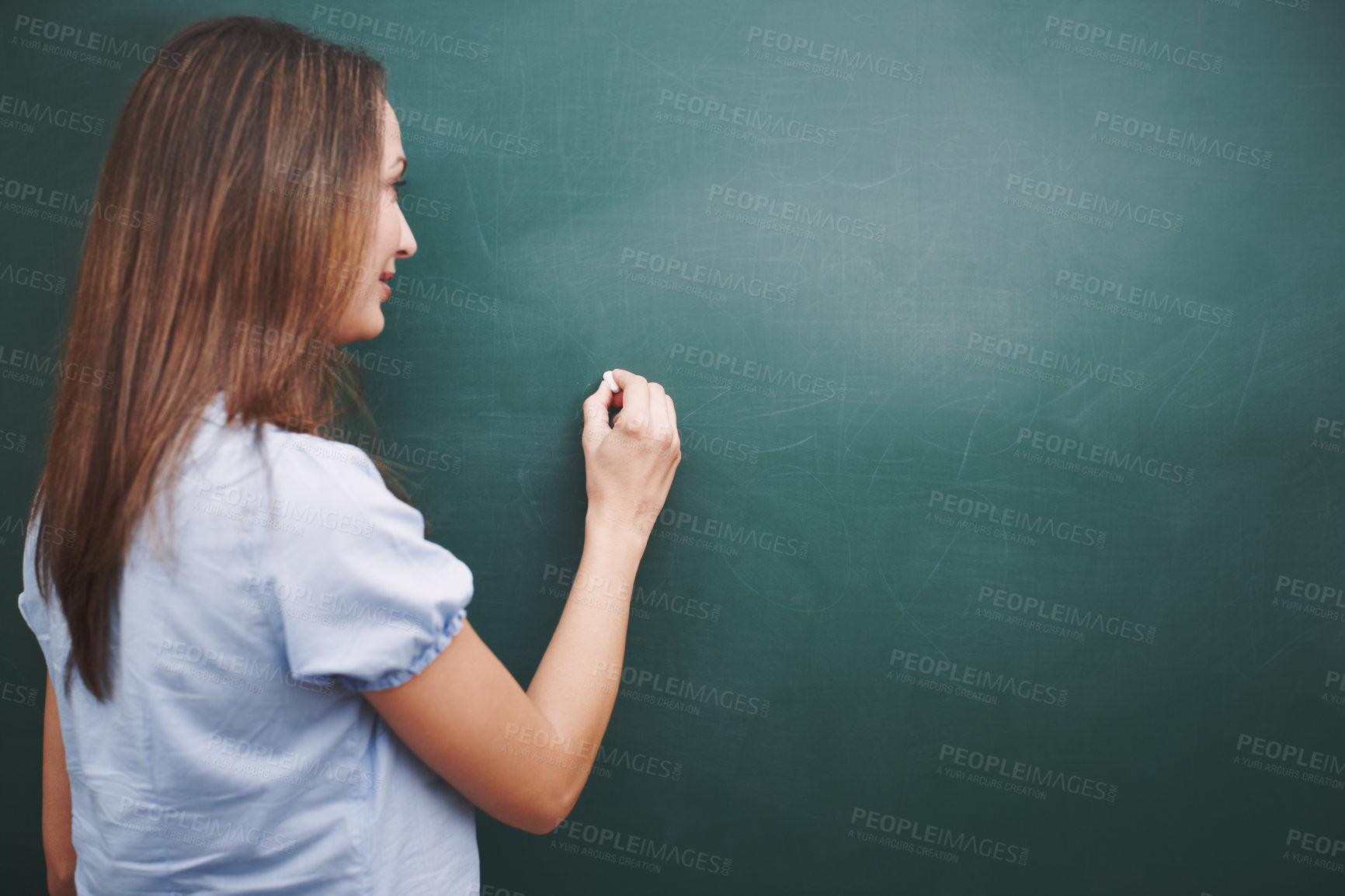 Buy stock photo A pretty young teacher writing  today's lesson plan on the blackboard