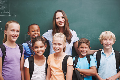 Buy stock photo A happy group of schoolkids standing at the blackboard with their pretty teacher