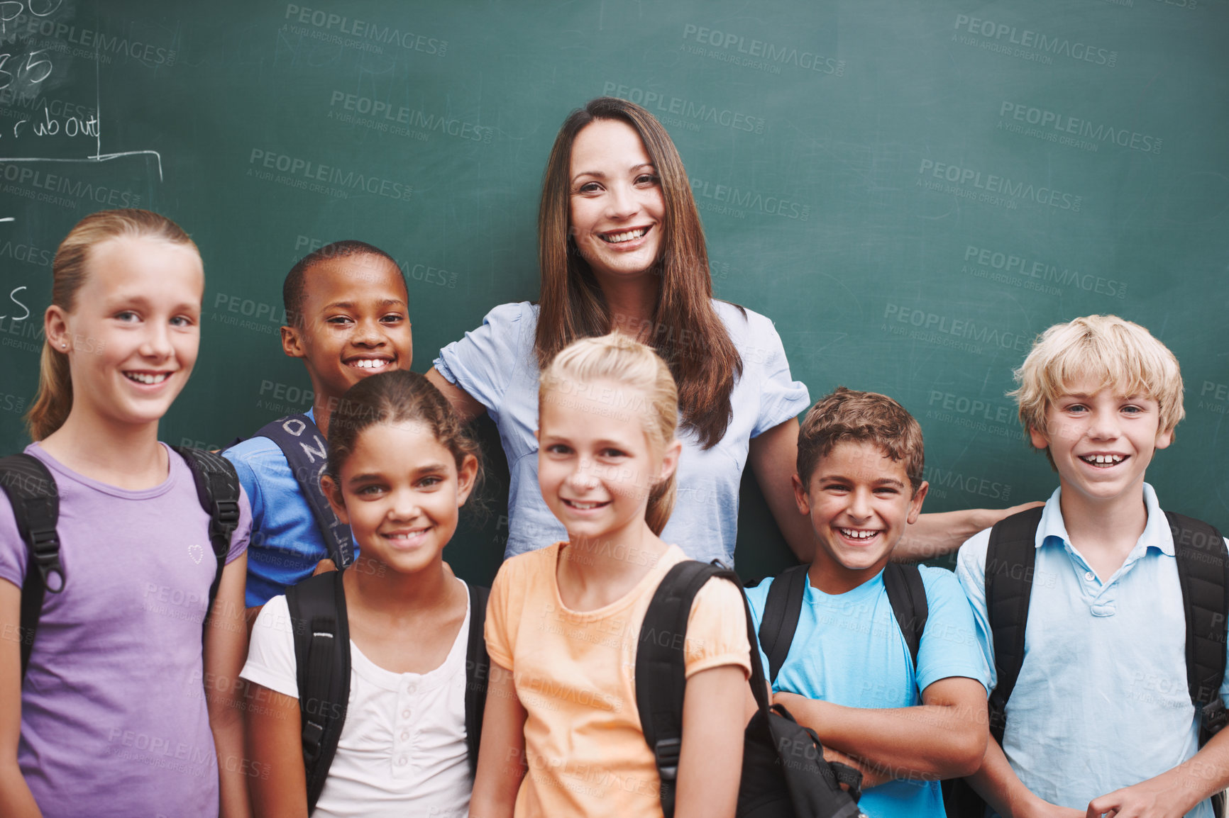 Buy stock photo A happy group of schoolkids standing at the blackboard with their pretty teacher