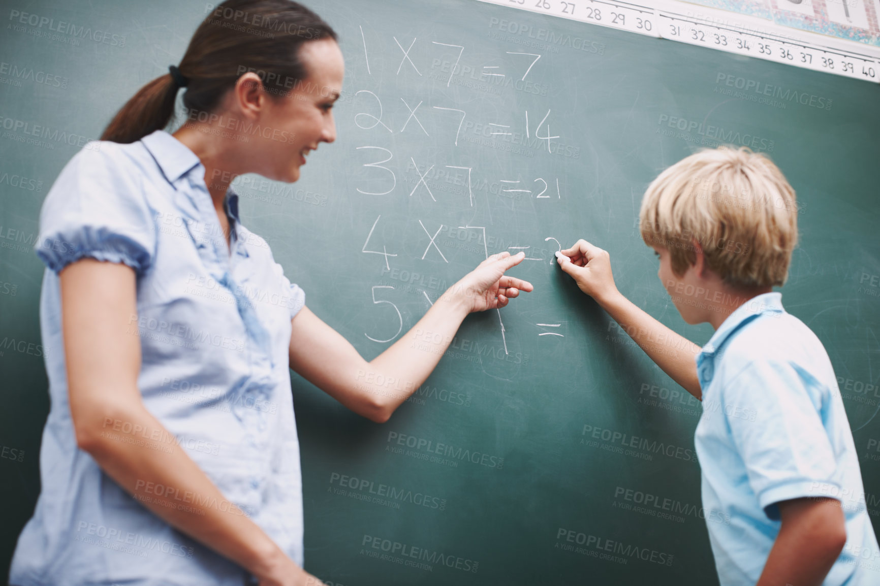 Buy stock photo Explain, maths and teacher helping student for knowledge, learning and support in classroom. Boy learner, chalkboard and writing with educator lady for lesson solution, problem solving and answer