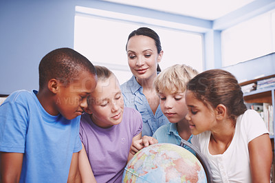 Buy stock photo A pretty young geography teacher teaching her students about the world using a globe of earth