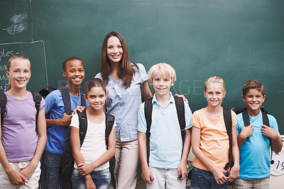 Buy stock photo Portrait, children and students with teacher, classroom and happy for education, group and diversity. School, woman and chalkboard in elementary, studying and kids with backpack, smile and learning