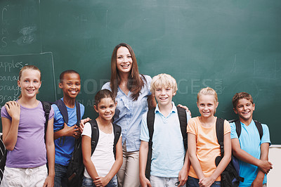 Buy stock photo Portrait, education and students with teacher, classroom and happy for learning, chalkboard and diversity. School, woman and kids in elementary, group and children with backpack, smile and studying