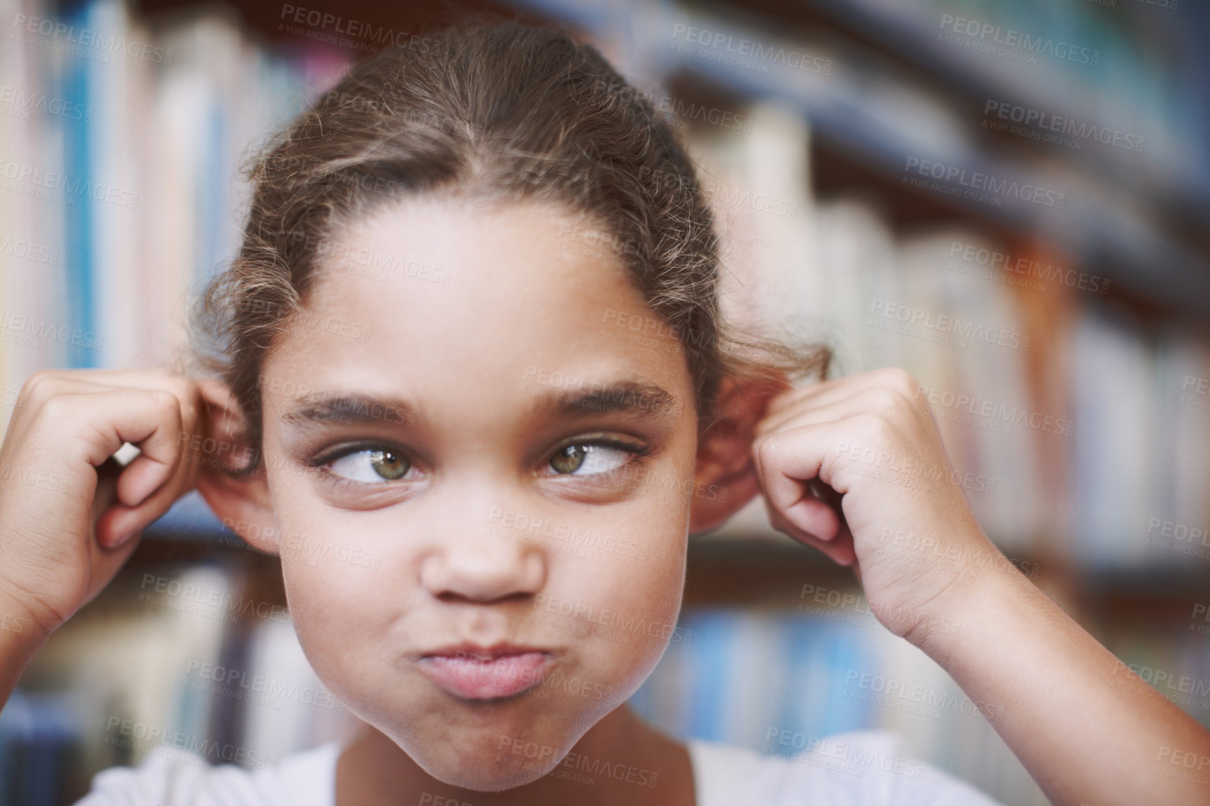 Buy stock photo Girl, child and funny face in pulling ears at school library on break for education, knowledge and learning. Female person, pupil and goofy or silly with squint eyes for playing, fun and childhood