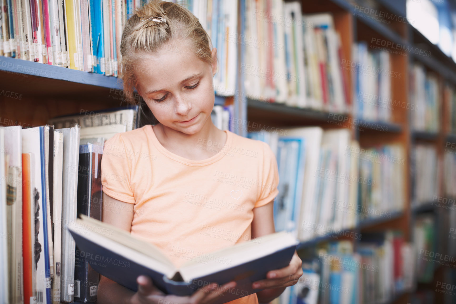 Buy stock photo Girl, library and serious for reading book at elementary school for literacy, knowledge and information. Student, kid and concentrate with fairytale, novel and literature for brain development