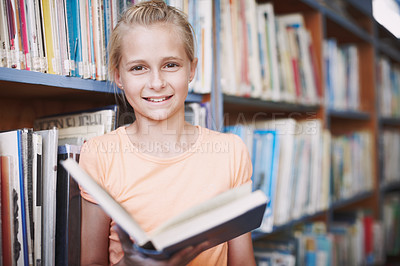 Buy stock photo Portrait of a cute young girl reading a book in the library