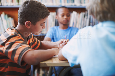 Buy stock photo A young boy concentrating on his work while at the library with his classmates