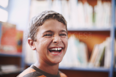 Buy stock photo An excited young boy sitting in the library and laughing happily