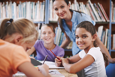Buy stock photo A young girl sitting in the library working with her classmates