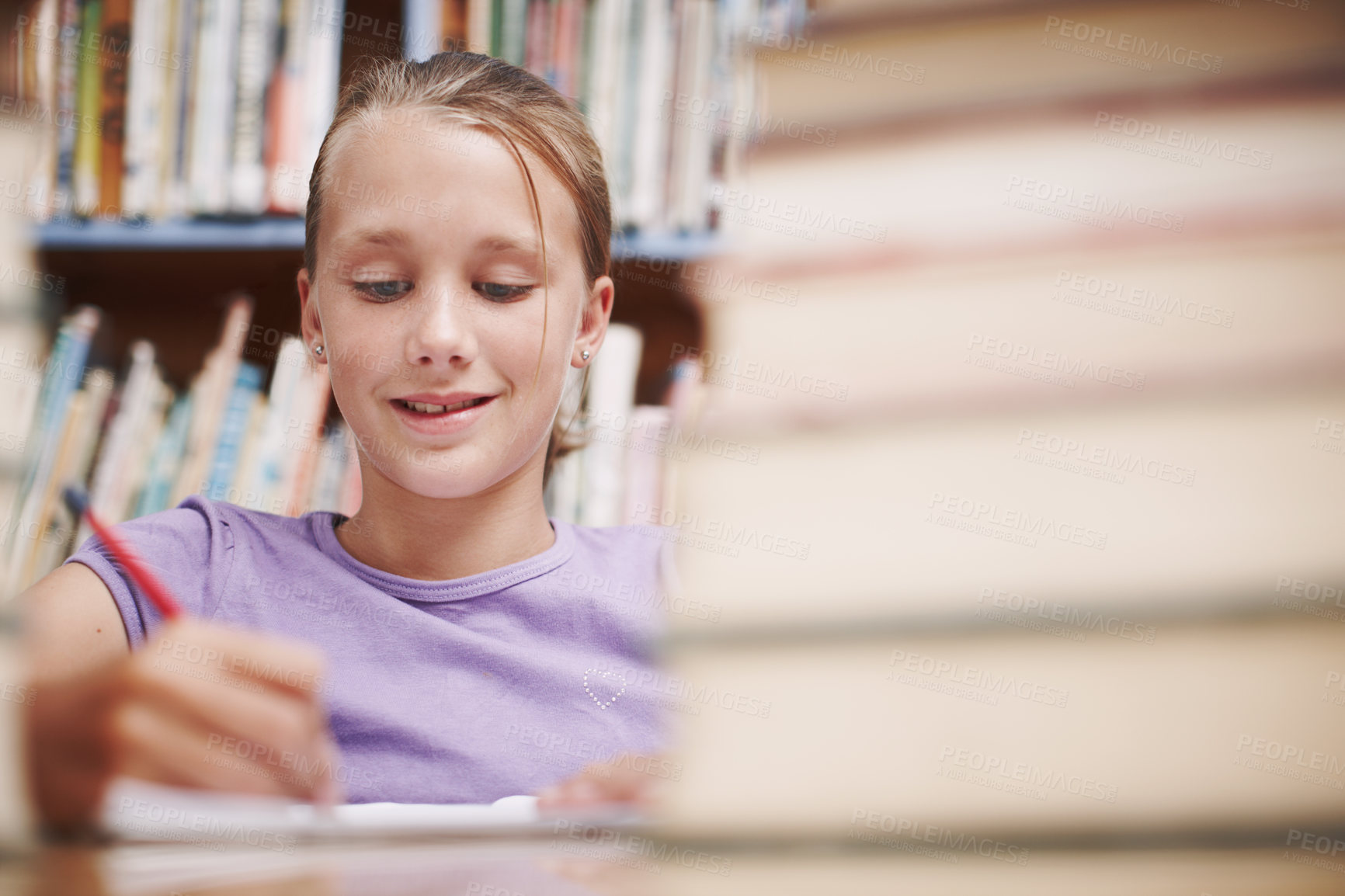 Buy stock photo Girl, writing and smile in library for education, knowledge and happy for development at elementary school. Young student, learning or books on table for fun lesson, growth and progress in assessment
