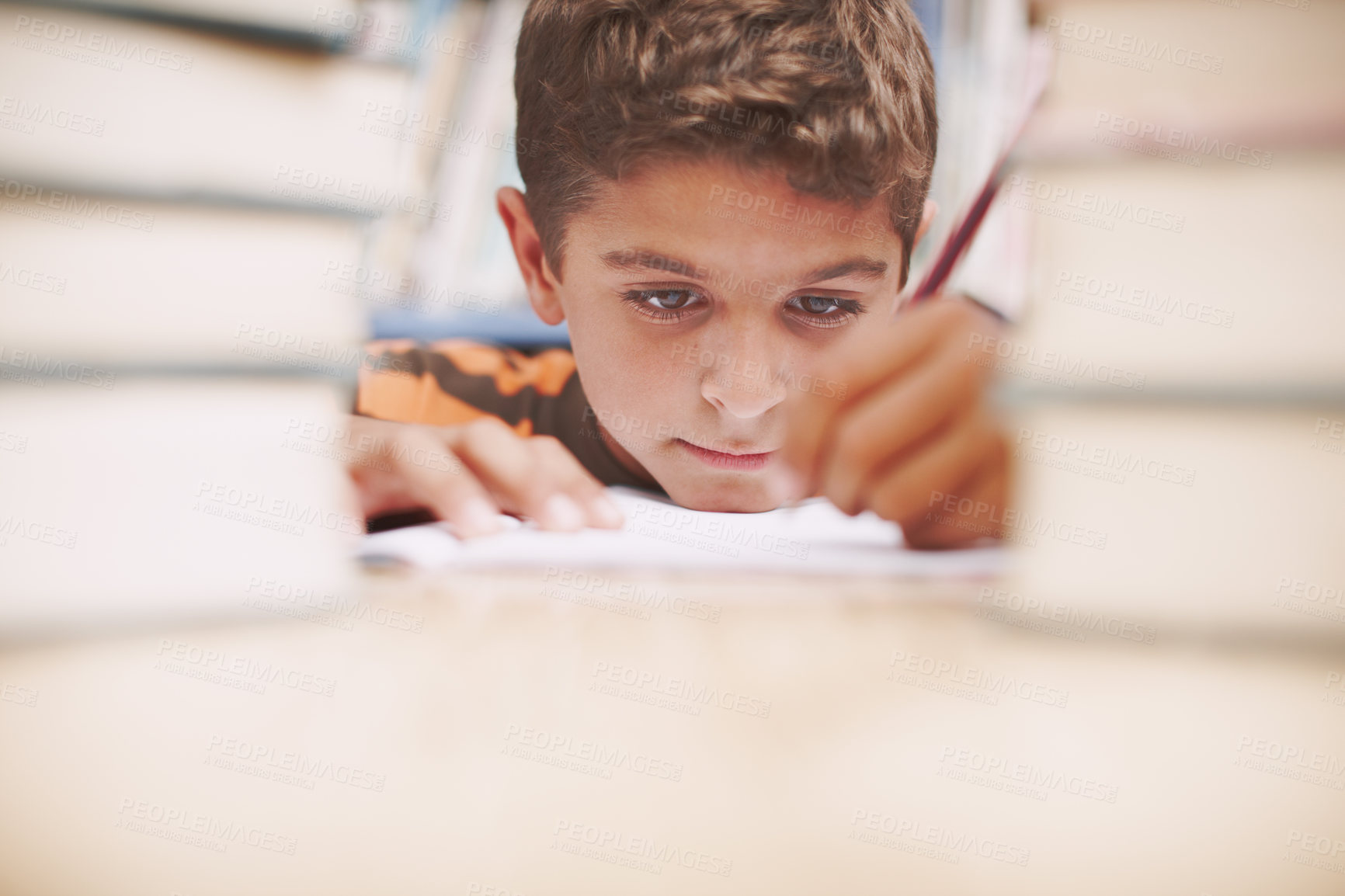 Buy stock photo Kid, writing and study in library for education, knowledge and solution for development at elementary school. Young boy, learning and books on table for lesson, growth and progress in assessment