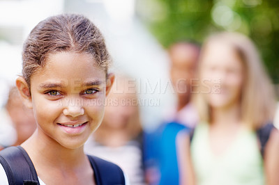 Buy stock photo Cute young multi-ethnic girl smiling at you with schoolmates blurred in background - copyspace