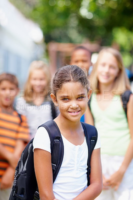 Buy stock photo Sweet young multi-ethnic girl standing in front of her school friends wearing a backpack