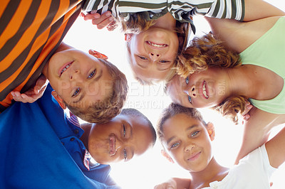 Buy stock photo Mixed race group of children standing in a circle looking down at the camera
