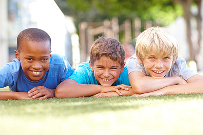 Buy stock photo Portrait of three cute boys lying on the grass on a sunny afternoon - copyspace