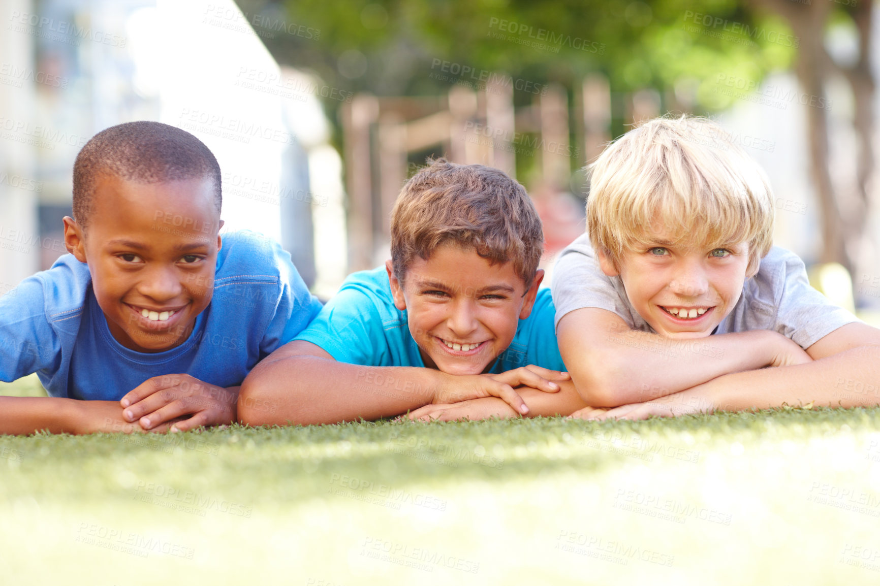 Buy stock photo Portrait of three cute boys lying on the grass on a sunny afternoon - copyspace