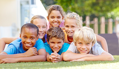 Buy stock photo A group of cute primary school kids lying down in pyramid formation outside 