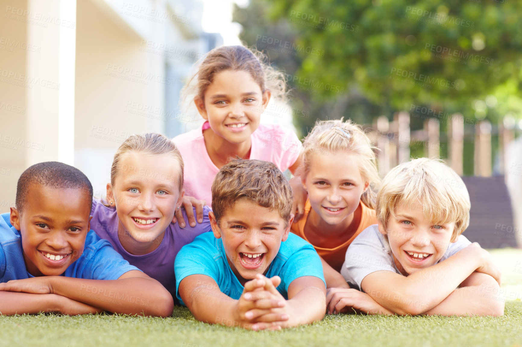 Buy stock photo Group portrait of happy school kids lying in a pile outside in the sun