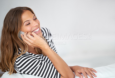 Buy stock photo Shot of a young woman talking on the phone while sitting on the sofa at home