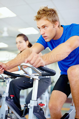 Buy stock photo Young man exercising with spinning bicycle at gym