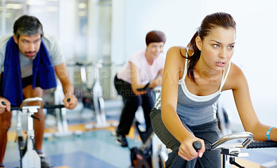 Buy stock photo Beautiful woman working out on a stationary bike at the gym