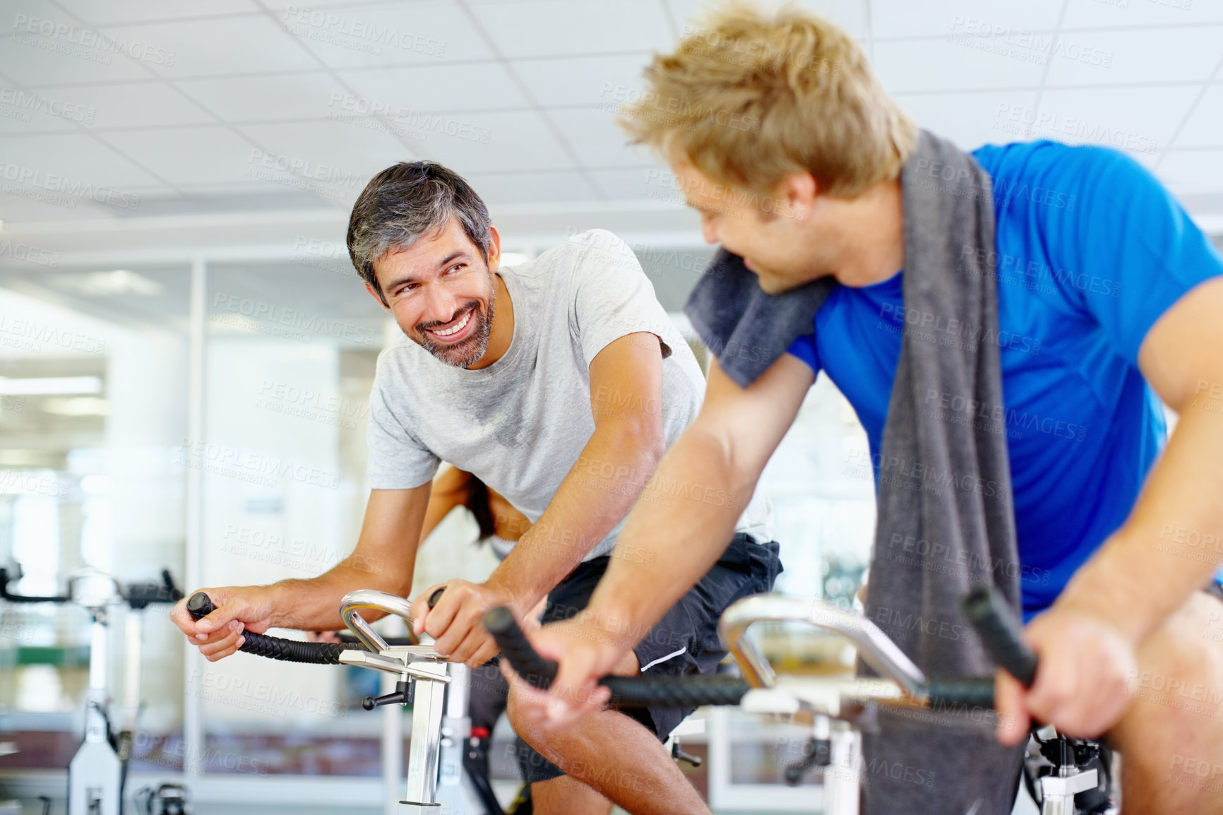 Buy stock photo Mature man talking with friends while spinning bicycle at the gym