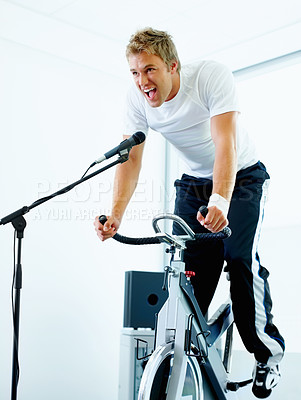 Buy stock photo Handsome man singing a song while cycling at the gym