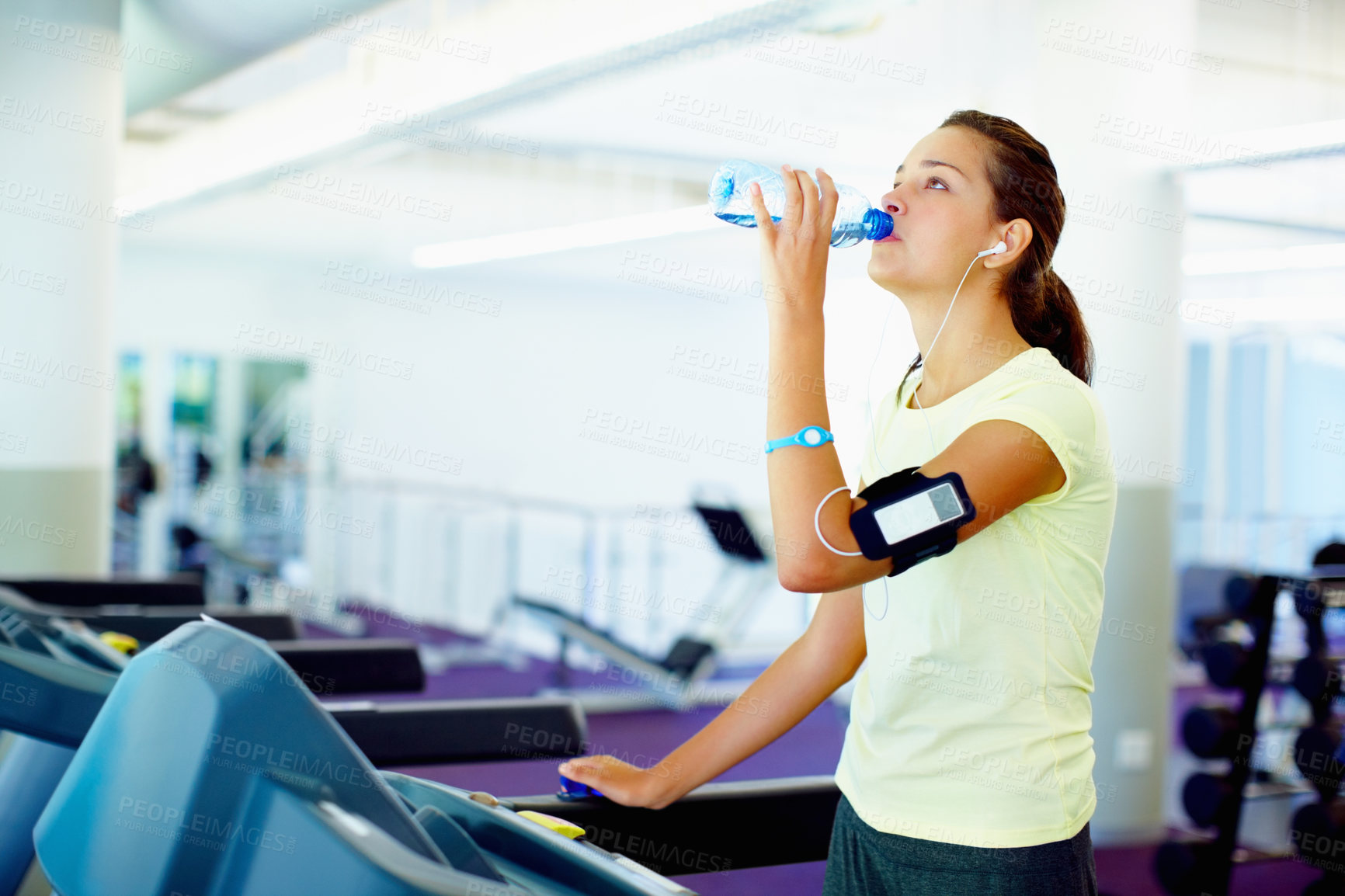 Buy stock photo Young woman standing on treadmill and drinking water