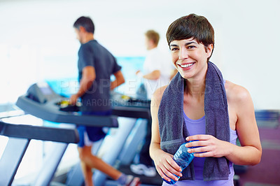 Buy stock photo Smiling woman having a bottle of water and looking away with people working out in background