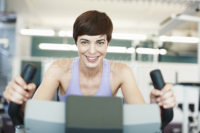 Buy stock photo Cropped portrait of an attractive young woman using an exercise bike in the gym