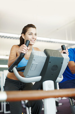 Buy stock photo Cropped shot of an attractive young woman using an exercise bike in the gym