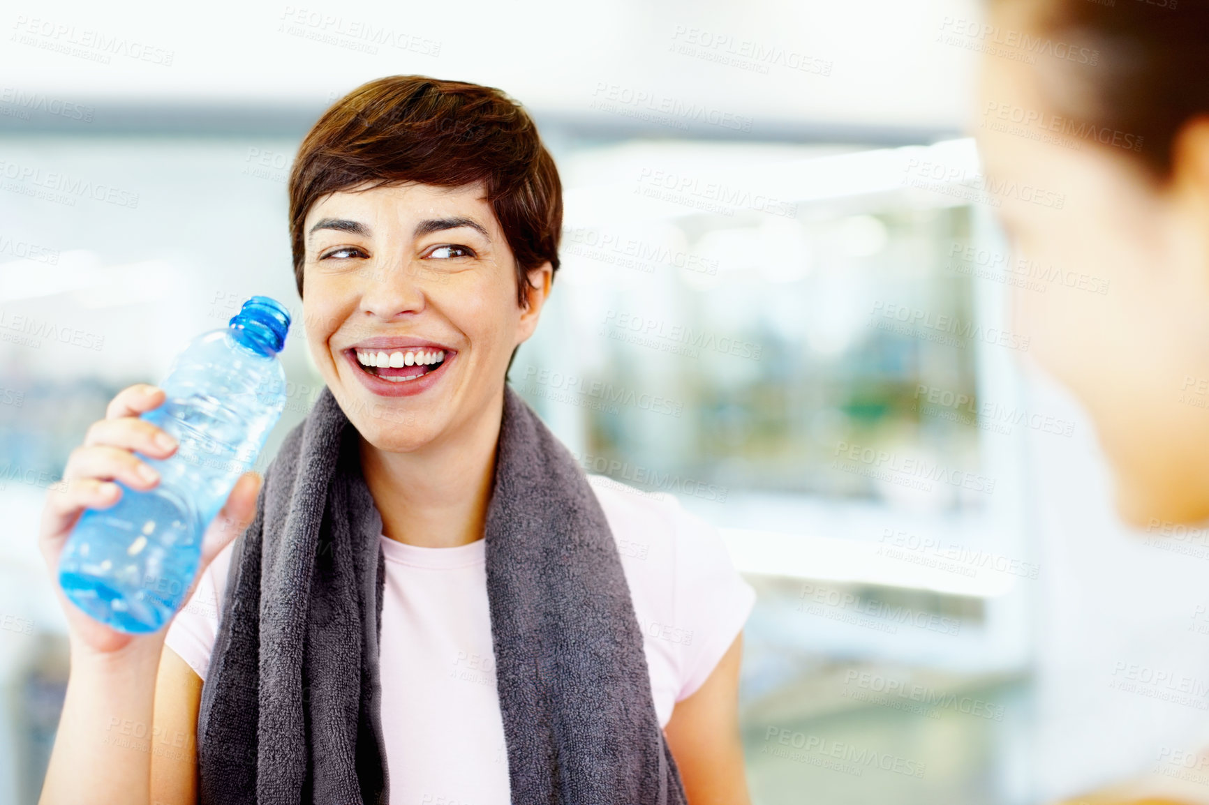 Buy stock photo Woman, water and laugh in gym for social, fitness update and joking with friend. Girl, towel and happy at wellness center for break, catch up and communication with person for funny story or feedback