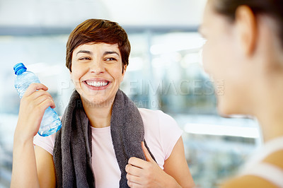Buy stock photo Woman holding water bottle while chatting with friends at fitness center