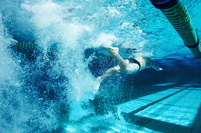Buy stock photo Rearview of a young male competitor swimming freestyle in a pool