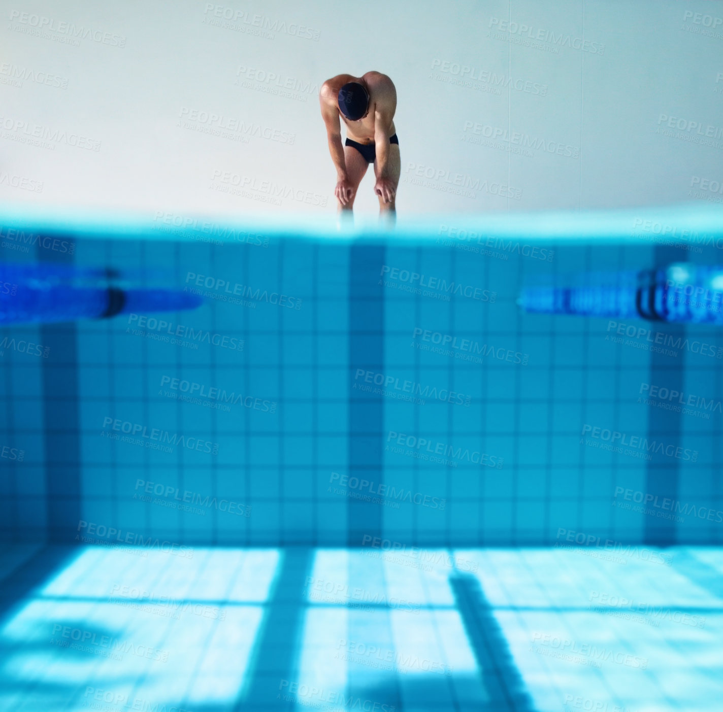 Buy stock photo A young male swimmer bending over with fatigue after a race