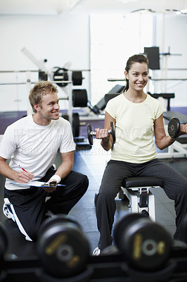 Buy stock photo Full length shot of an attractive young woman weight training with her personal trainer